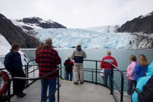 Visitors watch the calving Holgate Glacier on a boat trip into Kenai Fjords National Park. Locals that initially were against the creation of the park, now embrace it as a wonderful asset for the local economy. NPS photo by Jim Pfeiffenberger.