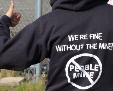 Shot of sweatshirt that says, "We're fine without the mine" and a slash through Pebble mine.
