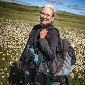 A photo of Nancy Lord in a field of wild flowers and grasses