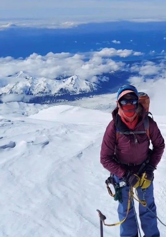 Teresa standing on a mountain summit.