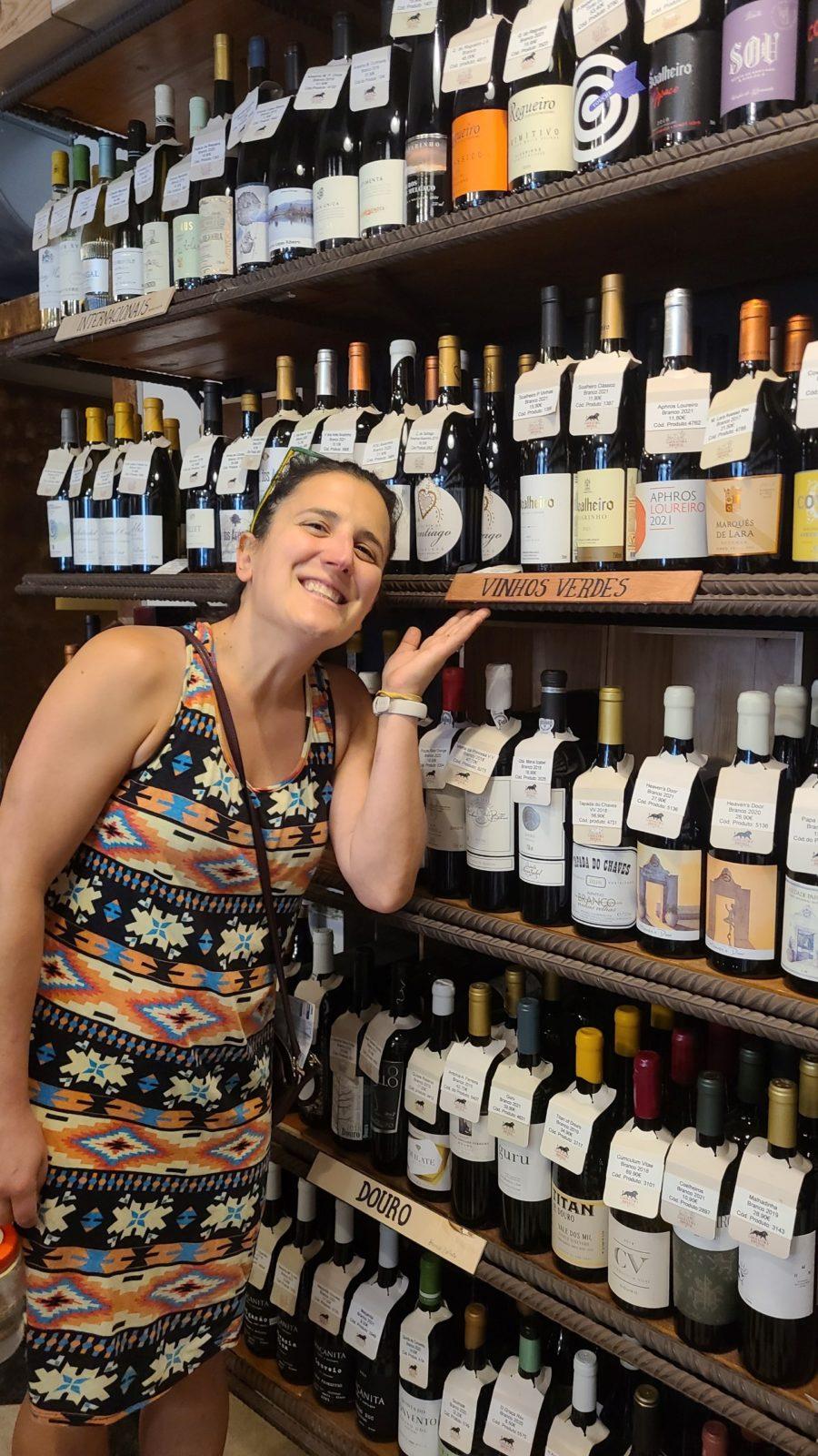 Bridget standing next to a wall of wine bottles in Portugal.